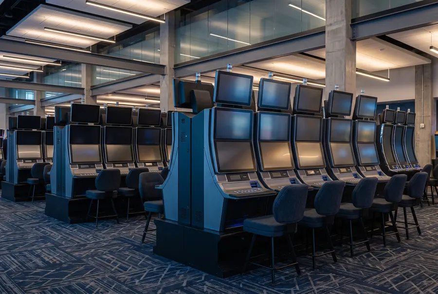 Generated scene: a row of slot machine cabinets in steel blue and graphite, screens showing abstract colour; not a photograph of the casino.